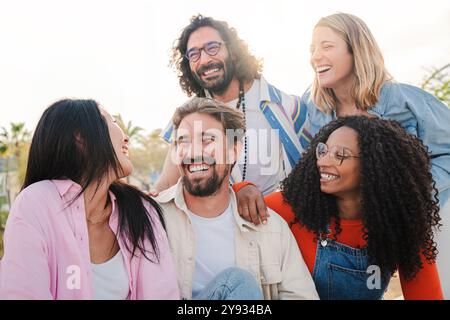 Gruppe von jungen erwachsenen Freunden, die sich unterhalten und Spaß haben, auf einem geselligen Treffen draußen. Multirassische Leute lächeln und unterhalten sich draußen. Verschiedene Typen auf einer lustigen Diskussion. Hochwertige Fotos Stockfoto