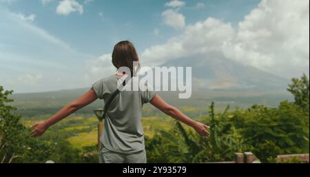 Die junge Frau genießt die atemberaubende Schönheit einer tropischen Landschaft mit dem majestätischen Mayon-Vulkan in der Ferne Stockfoto