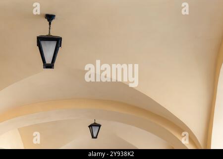 Vintage-geschmiedete Lampen sind an der weißen Bogendecke montiert Stockfoto