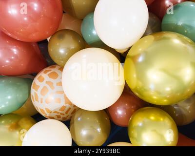 Viele Ballons in verschiedenen Farben, darunter blassgelb, hellgrün Metallic Gold und dunkelrot, bilden festlichen Hintergrund Stockfoto