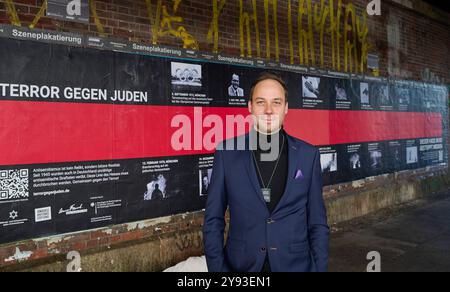 Kampagnenstart der Aktionswochen gegen Antisemitismus am 08.10.2024 mit einem 10 Meter langen Plakat am Hackeschen Markt in Berlin. Foto: Projektleiter der Aktionswochen gegen Antisemitismus Nikolas Lelle vor dem Plakat die Amadeu Antonio Stiftung und das Anne Frank Zentrum machen im Rahmen der diesjaehrigen Aktionswochen gegen Antisemitismus auf die anhaltende Bedrohung von Juedinnen und Juden aufmerksam. Mit der bundesweiten Plakatkampagne Terror gegen Juden erinnern die beiden Organisationen seit Dienstag bundesweit an die Opfer judenfeindlicher Straftaten seit 1945. Ziel der Kampagne ist d Stockfoto