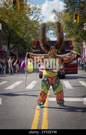 Ein Mann in einem sehr bunten Kostüm und hält Seilmärsche bei der Dominican Day Parade in Jackson Heights, Queens, New York. Stockfoto