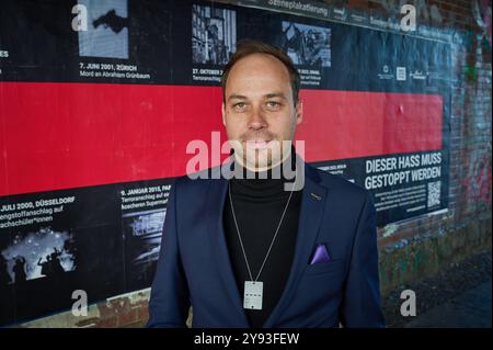 Kampagnenstart der Aktionswochen gegen Antisemitismus am 08.10.2024 mit einem 10 Meter langen Plakat am Hackeschen Markt in Berlin. Foto: Projektleiter der Aktionswochen gegen Antisemitismus Nikolas Lelle vor dem Plakat die Amadeu Antonio Stiftung und das Anne Frank Zentrum machen im Rahmen der diesjaehrigen Aktionswochen gegen Antisemitismus auf die anhaltende Bedrohung von Juedinnen und Juden aufmerksam. Mit der bundesweiten Plakatkampagne Terror gegen Juden erinnern die beiden Organisationen seit Dienstag bundesweit an die Opfer judenfeindlicher Straftaten seit 1945. Ziel der Kampagne ist d Stockfoto