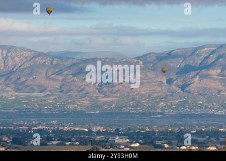 Heißluftballons über den spanischen Städten Rojales und Catral in der Provinz Alicante, Gemeinde Valencia, mit Gebirgszügen dahinter Stockfoto