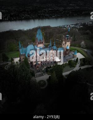 Blick aus der Vogelperspektive auf Schloss Drachenburg, ein märchenhaftes Schloss mit türkisfarbenen Dächern und gotischer Architektur auf einem üppigen Hügel am Rhein. Stockfoto