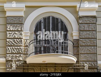 Detail einer gebogenen französischen Tür mit einem halbkreisförmigen Balkon an der grau-weißen Fassade eines alten Gebäudes in Italien Stockfoto