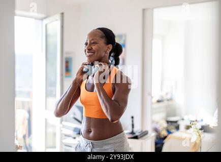 Lächelnde Frau in Sportkleidung zu Hause Stockfoto