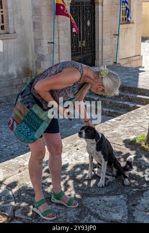 Die Dame hält auf der Straße an, um einen Hund zu streicheln oder zu streicheln, während sie in Griechenland Urlaub macht Stockfoto