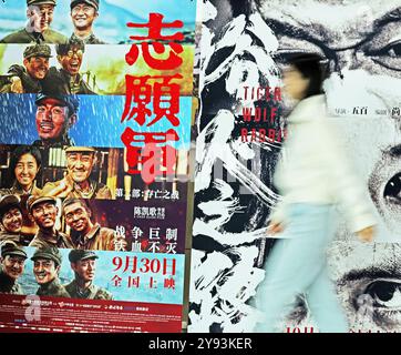 Peking, Chinas Provinz Shandong. Oktober 2024. Eine Frau läuft an Filmplakaten in einem Kino in Tancheng County, ostchinesischer Provinz Shandong, 7. Oktober 2024 vorbei. Quelle: Zhang Chunlei/Xinhua/Alamy Live News Stockfoto