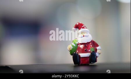 Eine kleine Figur des Weihnachtsmanns in einem rot-weißen Anzug mit grünem Sack vor einem verschwommenen Hintergrund. Das zeigt den Geist der weihnachten Stockfoto