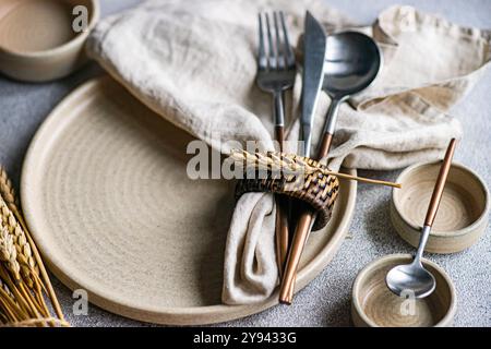 Dieses Bild zeigt einen wunderschön gestalteten herbstlichen Tisch mit natürlichen Tönen und Texturen. Ein Weizenstiel um Besteck gebunden sorgt für ein warmes, har Stockfoto