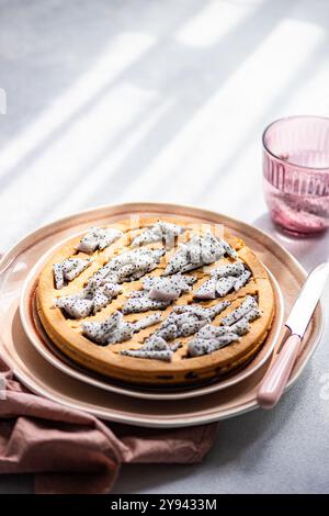 Ein frisch gebackener Drachenfruchtkuchen, garniert mit Scheiben Drachenfrucht, serviert auf einer stilvollen Keramikplatte neben einem rosafarbenen Glas Stockfoto