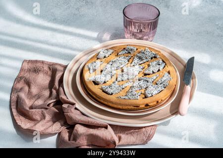 Ein frisch gebackener Kuchen, der mit Scheiben Drachenfrucht geschmückt ist, auf gestapelten Keramikplatten platziert wird. Ein dezentes Schattenmuster verstärkt die Textur, während ein staubiger Kuchen entsteht Stockfoto