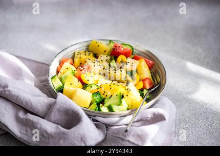 Von oben ein lebendiger Gemüsesalat mit roten und gelben Tomaten, Gurke, Paprika und Sesamsamen, serviert in einem metallischen B Stockfoto