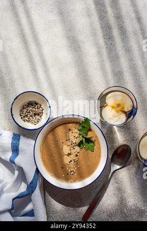 Blick von oben auf ein gesundes Abendessen mit Pilzcremesuppe garniert mit Petersilie und Samen, begleitet von einem Glas Apfelwasser mit frischem sl Stockfoto