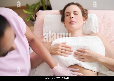 Von oben eine entspannende Hausmassage mit einer Patientin, die sich mit geschlossenen Augen liegend, und beschnittene, nicht erkennbare Masseurin Profes Stockfoto