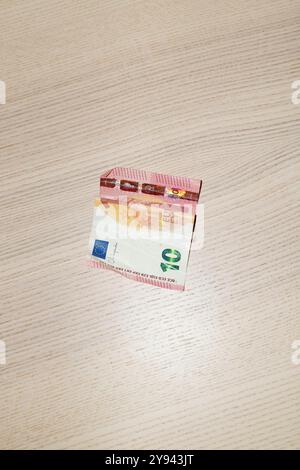 Eine 10-Euro-Banknote befindet sich auf einem hellen, strukturierten Holztisch und hebt ihre Farben und Details in einer Nahaufnahme hervor. Stockfoto