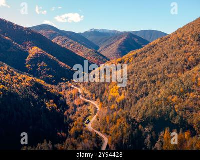 Eine atemberaubende Luftaufnahme einer kurvenreichen Straße, die sich im Herbst durch die aragonesischen Pyrenäen schlängelt, das bunte Laub des umliegenden Waldes c Stockfoto