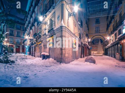 Eine ruhige Winternächteszene in Madrid, Spanien, mit schneebedeckten Straßen und wunderschön beleuchteten Lampen, die den bezaubernden Bogen der Stadt hervorheben Stockfoto