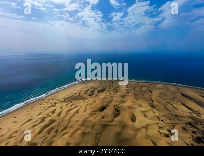 Luftbild mit einem weiten Blick auf die Maspalomas Dunes mit goldenen Sandmustern am türkisfarbenen Meer unter einem teilweise bewölkten Himmel Stockfoto