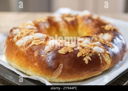 Frisch gebackener traditioneller Three Kings Cake, garniert mit Mandelscheiben und Zucker, präsentiert auf einer Küchentheke, symbolisiert die Epiphany Stockfoto
