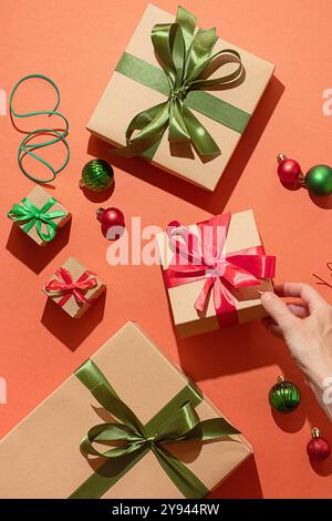 Eine festliche Szene mit mehreren Weihnachtsgeschenken, die in edles Papier mit leuchtenden roten und grünen Bändern auf rotem Hintergrund von einem unbekannten per gewickelt sind Stockfoto