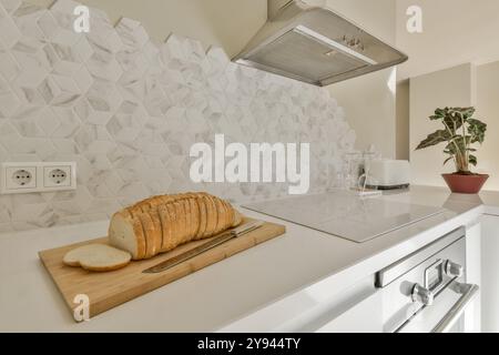 Die moderne Küche verfügt neben modernen Geräten über strukturierte Backspritzer, in Scheiben geschnittenes Brot auf einem Holzbrett. Stockfoto