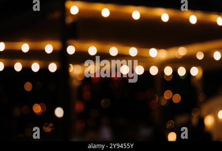 Warme, verschwommene Lichterketten schaffen ein festliches Ambiente auf diesem bezaubernden Nachtfoto, das in New York City aufgenommen wurde. Ideal für Hintergründe oder Urlaubsthemen Stockfoto