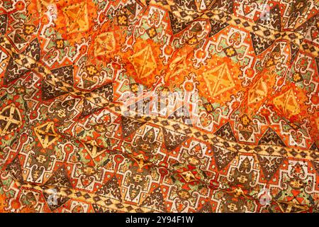 Traditionelles persisches Textil mit komplexen geometrischen Mustern in Orange, Braun und Grün. Stockfoto