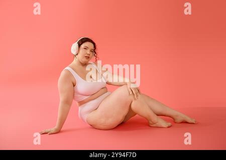 Diese atemberaubende Frau in Übergröße zeigt Selbstvertrauen und Schönheit mit einem leuchtend rosa Hintergrund. Stockfoto