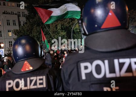 Berlin, Deutschland. Oktober 2024. Pro-palästinensische Demonstranten schwenken palästinensische Flaggen, während sie Slogans singen, während Polizeibeamte während eines Protests für palästinensische Rechte am ersten Jahrestag der Hamas-Invasion in Südisrael in Berlin Wache halten. Der Protest unter dem Motto „Glory to the Resistance“ wurde von einer großen Polizeipräsenz begleitet. Am 7. Oktober 2023 stürmten Tausende von Hamas-Militanten vom Gazastreifen nach Israel, töteten 1.139 Menschen und entführten Israelis. Quelle: SOPA Images Limited/Alamy Live News Stockfoto