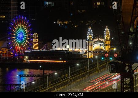 Sydney, Australien - 9. Februar 2023: Lange Fahrt von Autos über die Sydney Harbour Bridge bei Nacht, mit dem berühmten Luna Park Jahrmarkt auf der anderen Seite der Bucht. Stockfoto