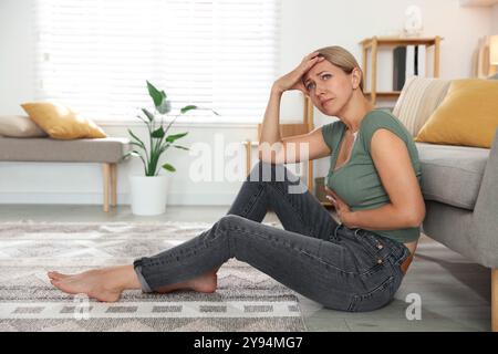 Wechseljahre. Frau mit Bauchschmerzen auf dem Boden zu Hause Stockfoto