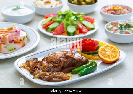 Eintopf aus persischer Lammkeule mit karamelisierten Zwiebeln und frischem Salat, garniert mit Kräutern und Zitrusfrüchten. Stockfoto