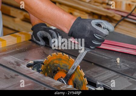 Zimmermann ersetzt eine Kreissäge in einer Werkzeugmaschine. Austausch der Säge in der Tischlerei Stockfoto