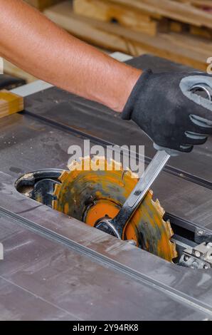 Zimmermann ersetzt eine Kreissäge in einer Werkzeugmaschine. Austausch der Säge in der Tischlerei Stockfoto