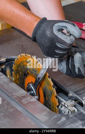 Zimmermann ersetzt eine Kreissäge in einer Werkzeugmaschine. Austausch der Säge in der Tischlerei Stockfoto