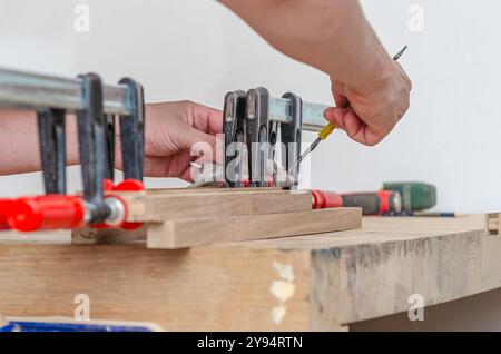 Befestigung von Schreinerklammern an einem Holzgestell in einer Schreinerei, Verkleben von Brettern Stockfoto