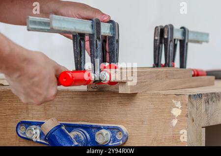 Befestigung von Schreinerklammern an einem Holzgestell in einer Schreinerei, Verkleben von Brettern Stockfoto