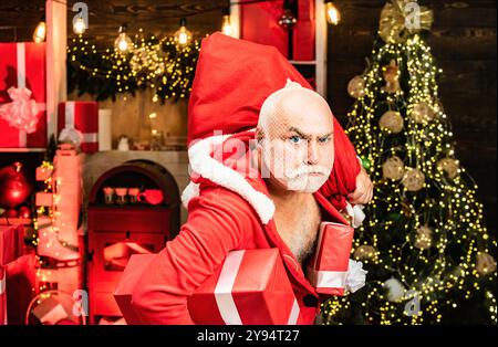 Gefährlicher Einbrecher in Santa-Kostüm gekleidet. Santa in der Maske mit Tasche. Lustige Santas mit Taschen - Einbrecher oder Dieb Konzept. Stockfoto