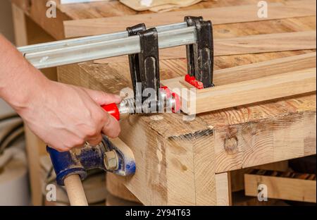 Befestigung von Schreinerklammern an einem Holzgestell in einer Schreinerei, Verkleben von Brettern Stockfoto