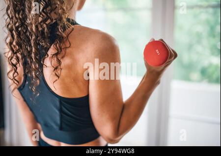 Nahaufnahme einer weißen weißen Frau, die alleine arbeitet und mit einem Arm zu Hause ein Hantelgewicht hebt (von Ivan Radic) Stockfoto