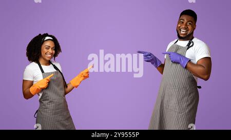 Beste Reinigungsideen. Positive Schwarze Paar In Handschuhe Zeigt Auf Copy Space Stockfoto
