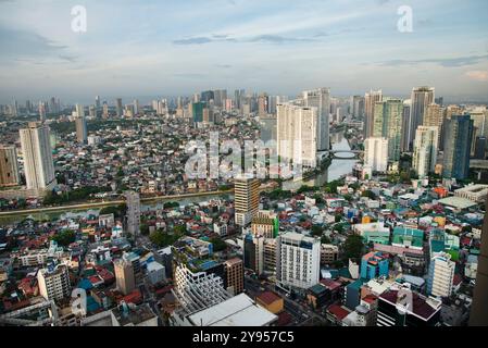 Manila, Philippinen-16. Mai 2023: Der Pasig River fließt bei Sonnenuntergang durch die Hauptstadt, umgeben von einer Mischung aus hoher moderner Architektur und armen Wohnhäusern Stockfoto