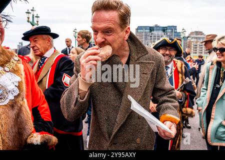 Hollywood-Schauspieler Damian Lewis isst Einen Donut zum Frühstück, bevor er den Annual Sheep Drive über die Southwark Bridge in London führt. Stockfoto