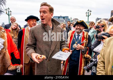 Hollywood-Schauspieler Damian Lewis isst Einen Donut zum Frühstück, bevor er den Annual Sheep Drive über die Southwark Bridge in London führt. Stockfoto