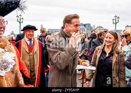 Hollywood-Schauspieler Damian Lewis isst Einen Donut zum Frühstück, bevor er den Annual Sheep Drive über die Southwark Bridge in London führt. Stockfoto