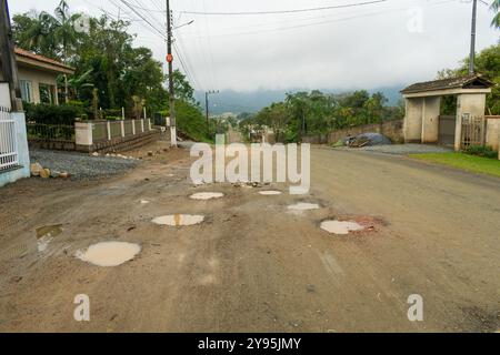 Viele Schlaglöcher auf einer unbefestigten Straße in einem Wohnviertel in Schroeder, Santa Catarina, Brasilien Stockfoto