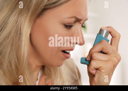 Frau mit Asthma-Inhalator in Innenräumen, Nahaufnahme Stockfoto