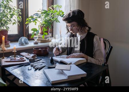 Engagierte, nachdenkliche Künstlerin erstellt Skizzen mit Stift und Pinsel in Notizbuch. Freiberuflicher Job Stockfoto